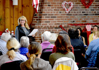 A photo of a person giving a speech about caregiving in front of a crowd at a senior center.